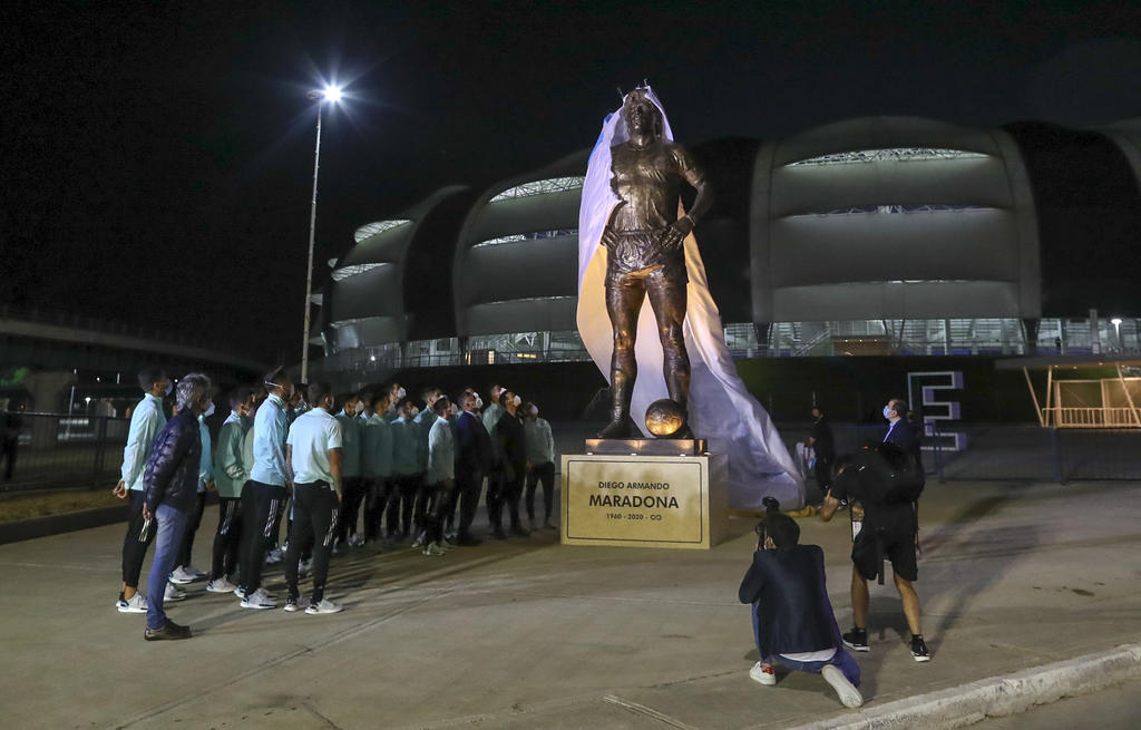 Jugadores de la selección argentina presencian la develación de una estatua de Diego Maradona frente al Estadio Madre de Ciudades, antes de su partido de la eliminatoria mundialista ante Chile en Santiago del Estero, el jueves 3 de junio de 2021 (Agustin Marcarian, Pool via AP)