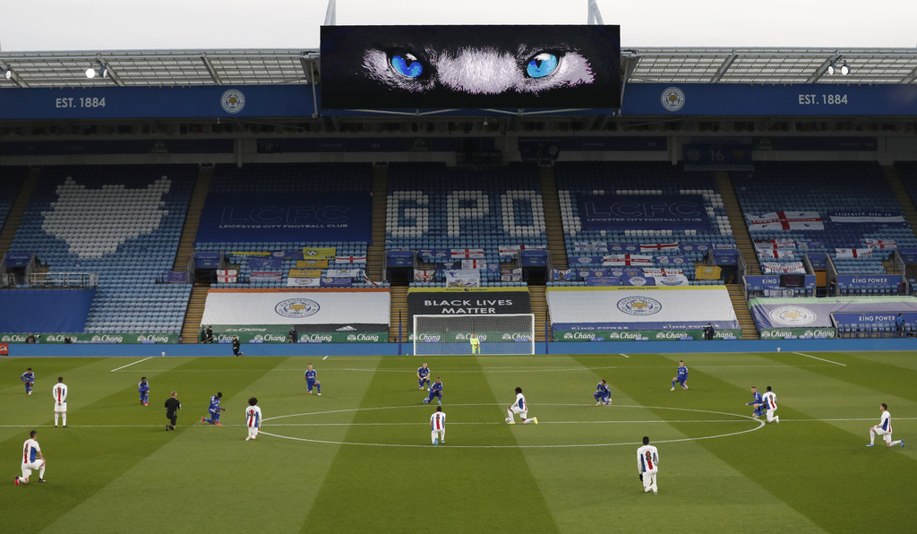 Futbolistas apoyan una rodilla en el césped para manifestarse contra el racismo, antes de un partido entre Leicester City y Crystal Palace.