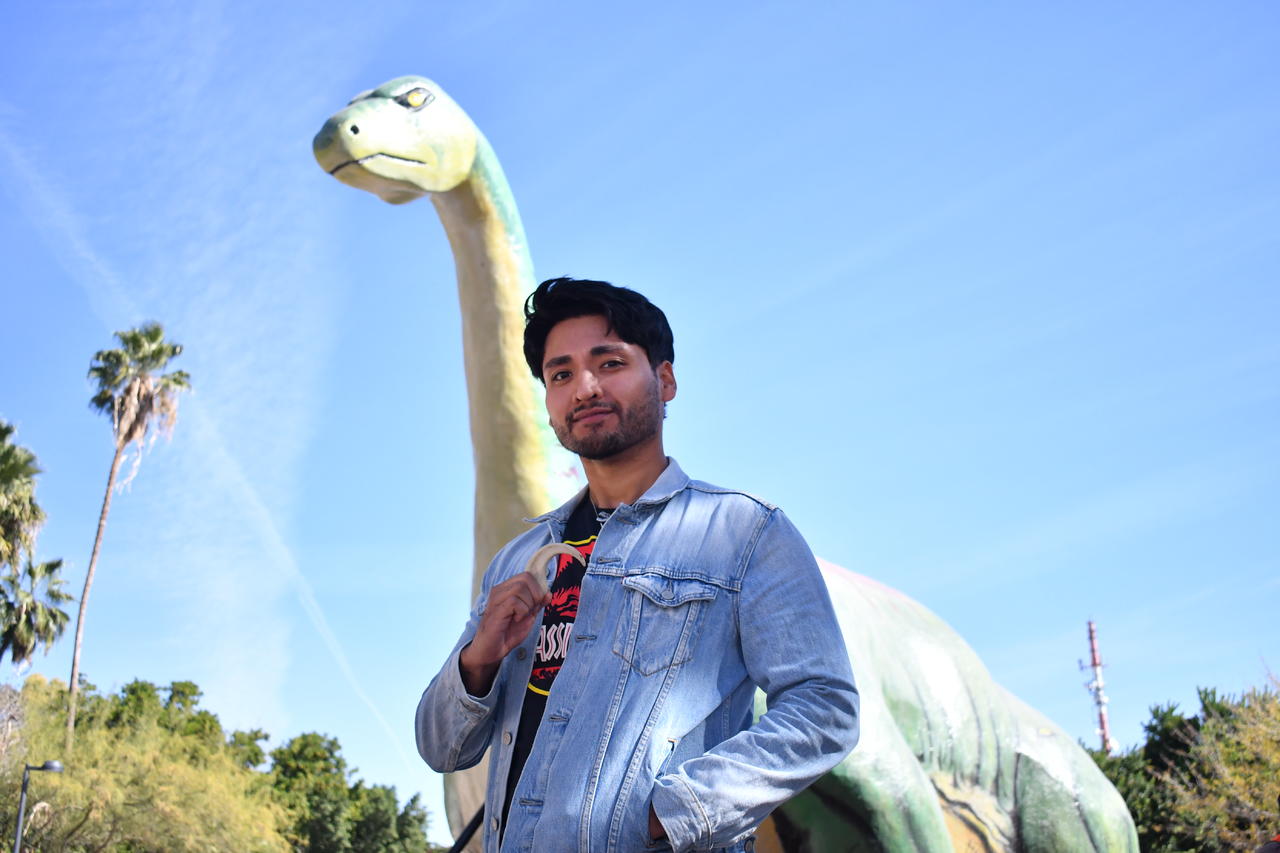 El repintado del dinosaurio del Bosque Venustiano Carranza de Torreón, es uno de los proyectos más grandes que ha hecho Daniel, quien posó orgulloso con su garrita de velociraptor junto a su obra terminada (EL SIGLO DE TORREÓN/ADÁN RAMOS)