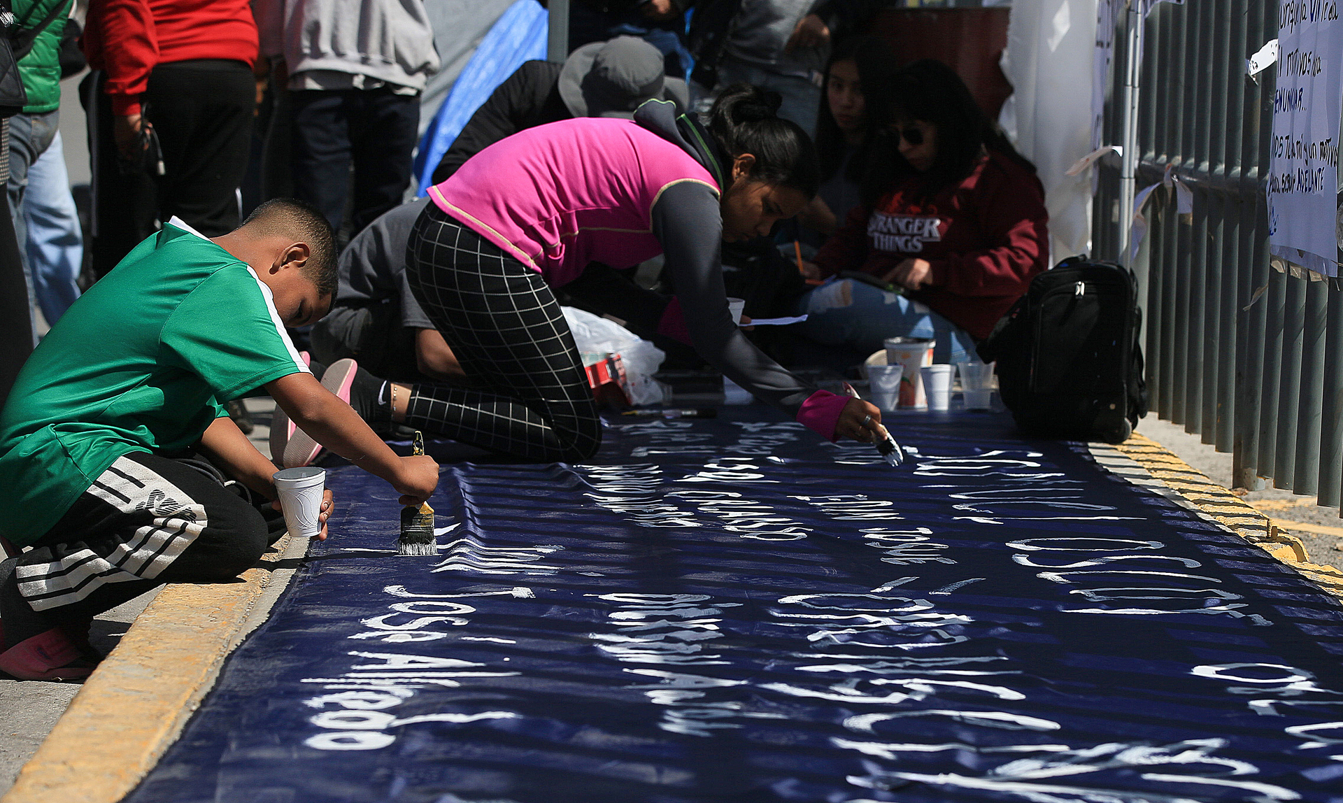 Migrantes escriben pancartas durante una manifestación para exigir justicia por 40 indocumentados que murieron por un incendio hace nueve días, hoy, al exterior del Instituto Nacional de Migración (INM), en Ciudad Juárez (México). Decenas de migrantes y dirigentes de colectivos encendieron veladoras este miércoles con el nombre de los 40 indocumentados que murieron por un incendio hace nueve días, para exigir justicia y un memorial a las autoridades de la fronteriza Ciudad Juárez, Chihuahua, al norte de México. EFE/Luis Torres.