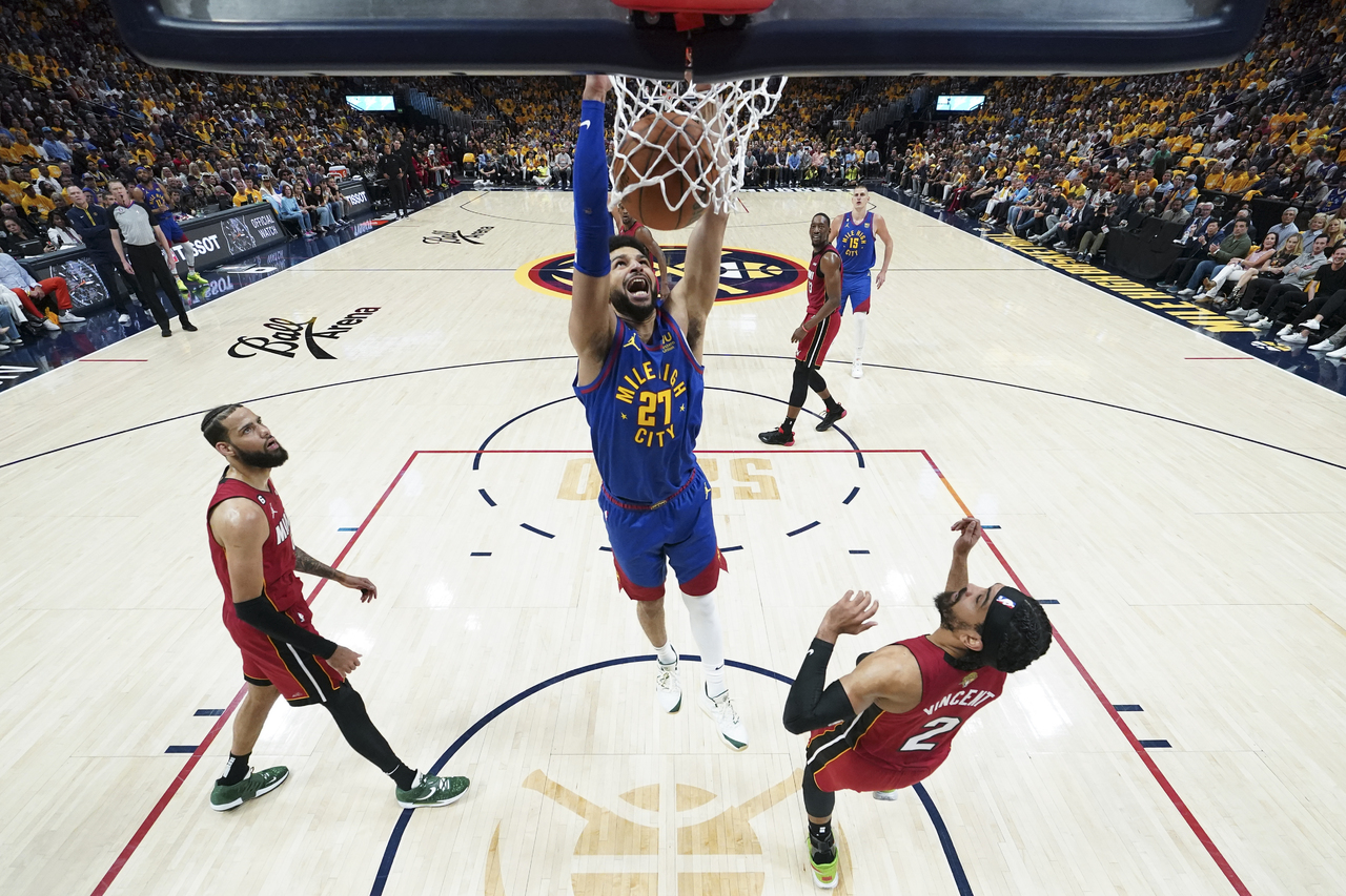 El guardia de Denver, Jamal Murray, clava la pelota en el aro rival sobre la marca de dos jugadores del Miami Heat, durante el primer juego.