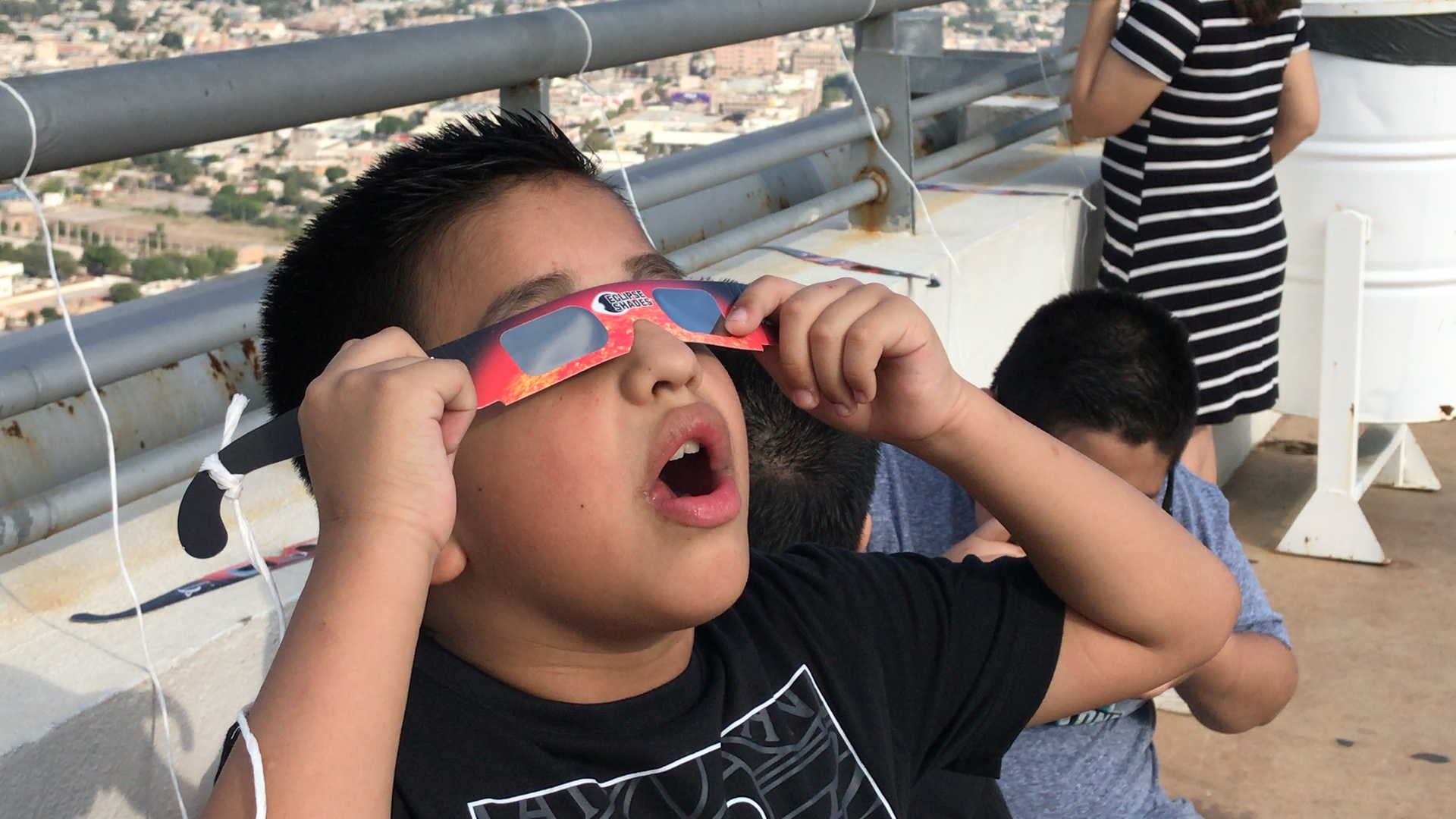 Niño usando lentes para ver el sol en el puerto noas. 