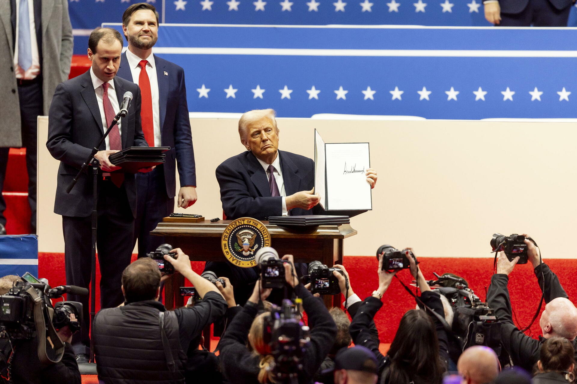 El presidente de Estados Unidos, Donald Trump (C), junto al vicepresidente estadounidense, JD Vance (2-I), mientras firma una serie de decretos en el escenario durante un acto inaugural presidencial en el Capitol One Arena en Washington, DC, EE.UU., el 20 de enero de 2025. EFE/EPA/ALLISON DINNER