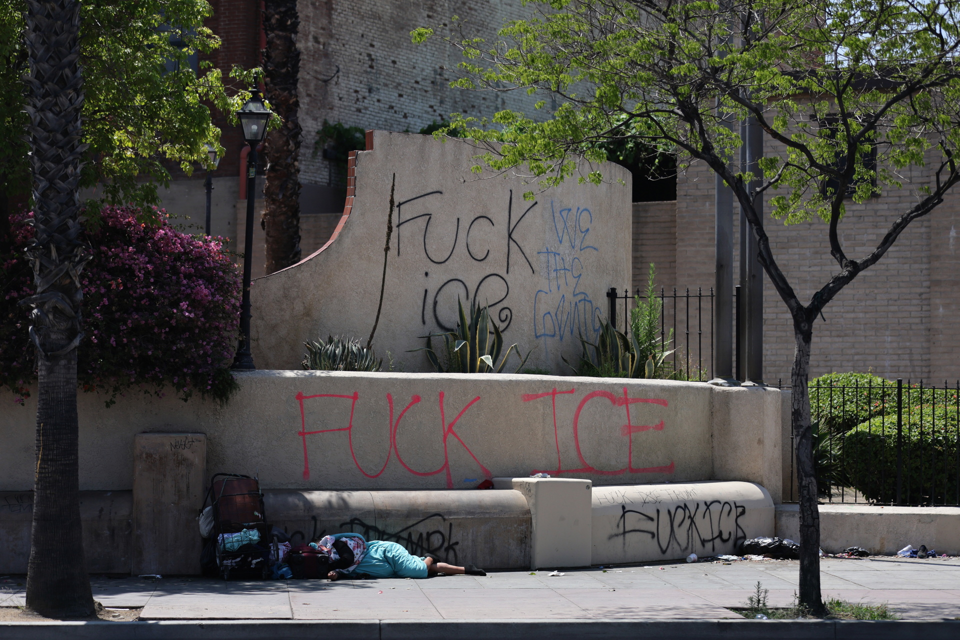 Una persona sin hogar duerme entre grafitis que atacan al Servicio de Inmigración y Control de Aduanas (ICE) durante las protestas provocadas por las redadas migratorias en Los Ángeles, California, el 10 de junio de 2025.