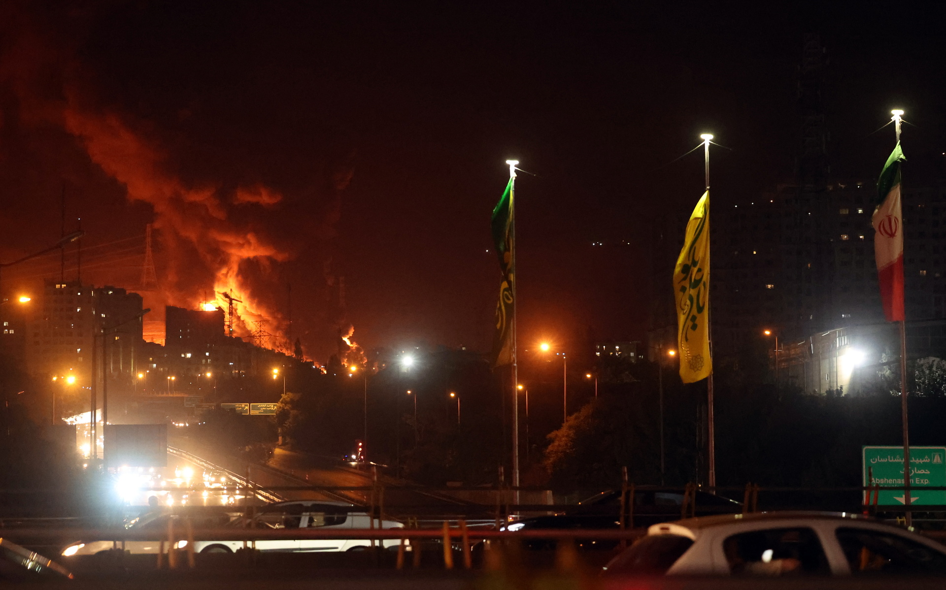 Personas conducen mientras se elevan llamas y humo desde un almacén de petróleo en Teherán, Irán / EFE